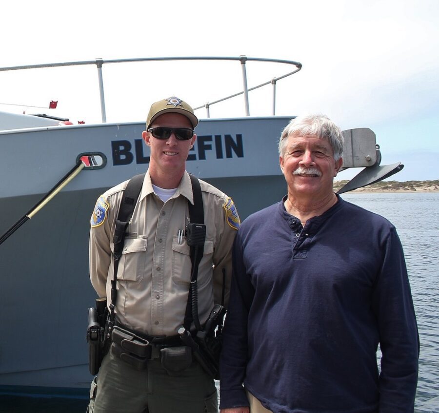 Author Steven T. Callan with Warden Ryan Hanson in front of the Fish and Wildlife Patrol Boat Bluefin