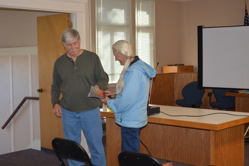A guest arrives to listen to author Steven T. Callan's presentation and to have him sign her copy of his latest book, The Case of the Missing Game Warden.