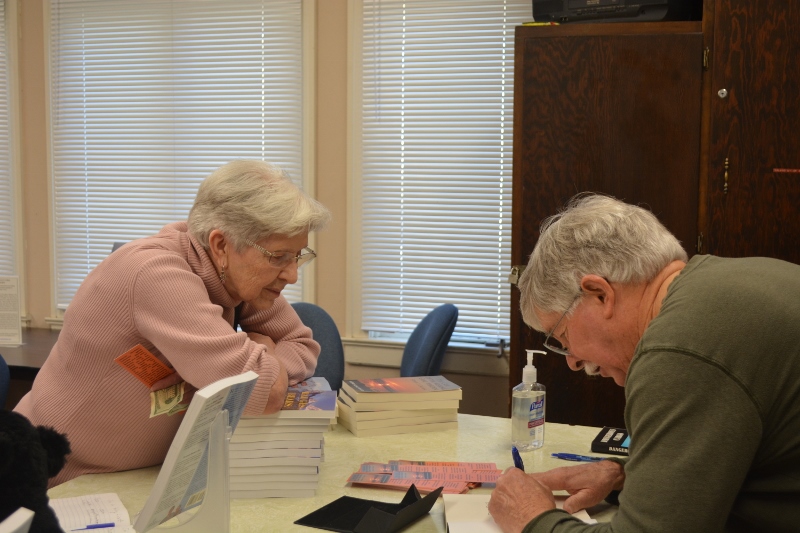 A visitor asks author Steven T. Callan to sign a copy of his latest book, The Case of the Missing Game Warden.